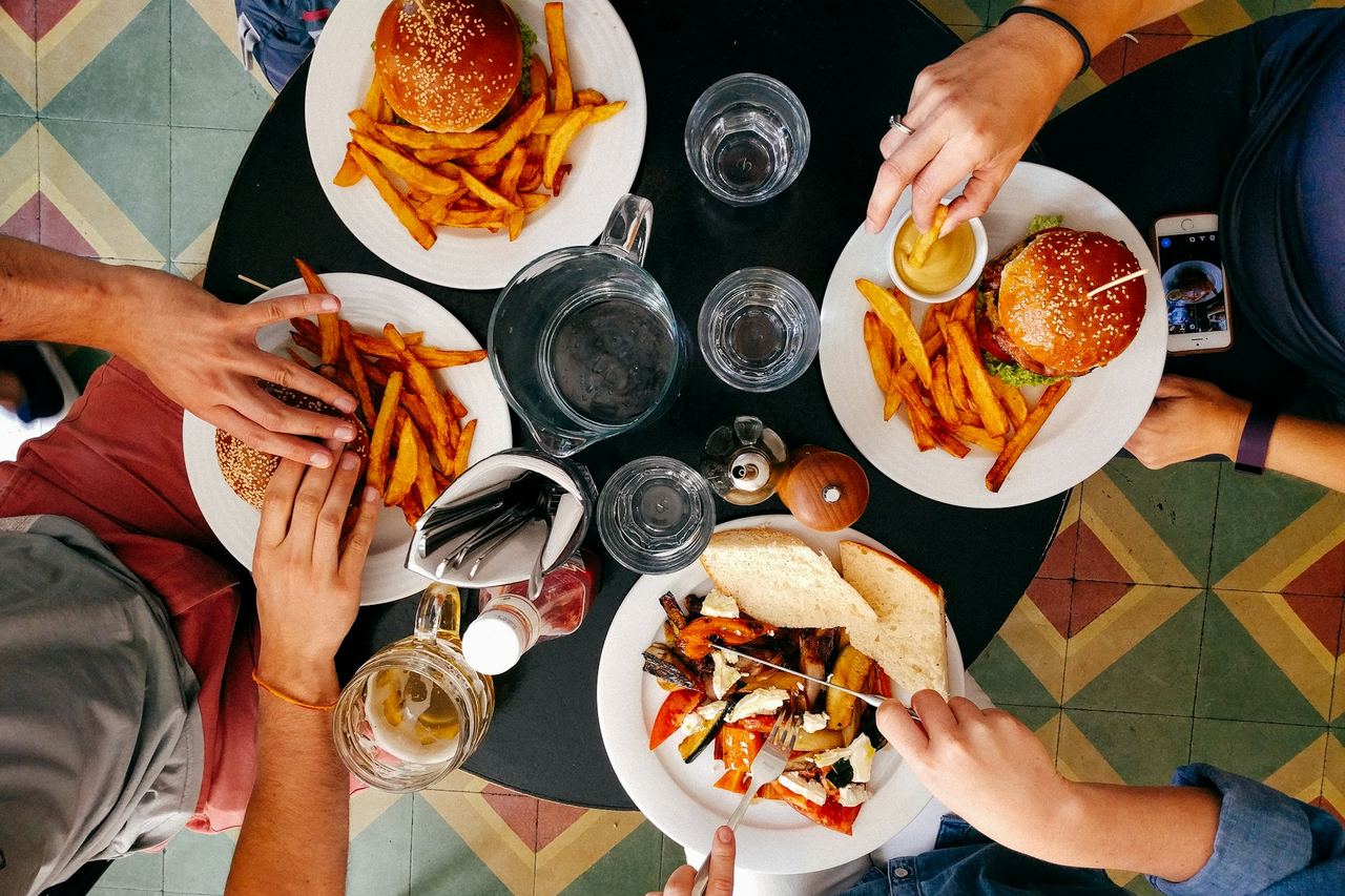 Friends sharing burgers and fries at a round table
