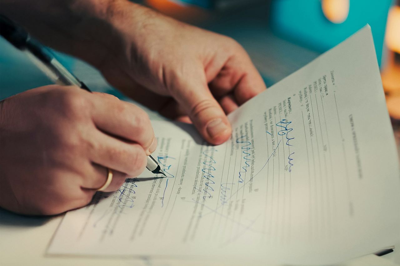 A man signing a document with a pen